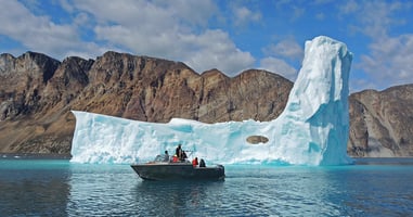 Group of arctic explorers on a boat observing a glacier