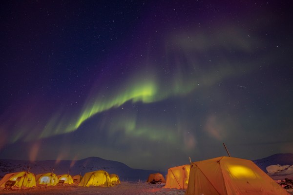 Heated tents below aurora borealis 