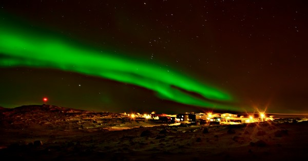 northern lights above city lights in the arctic