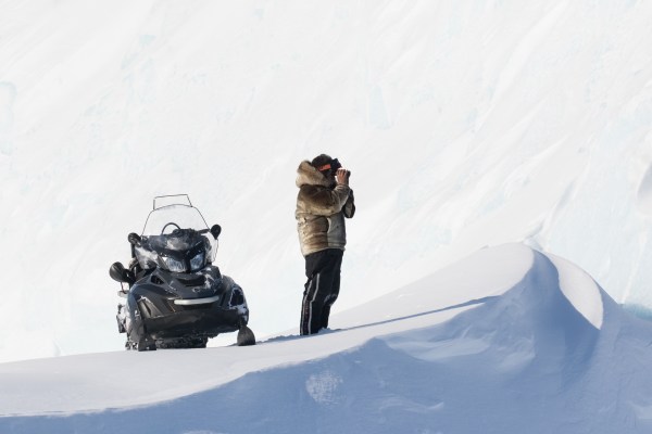 Snowmobile and guide scouting landscape in the arctic